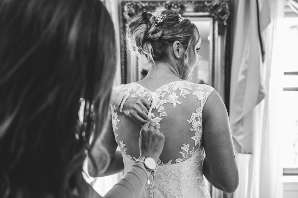 a bride putting on her wedding dress at hatherely manor hotel