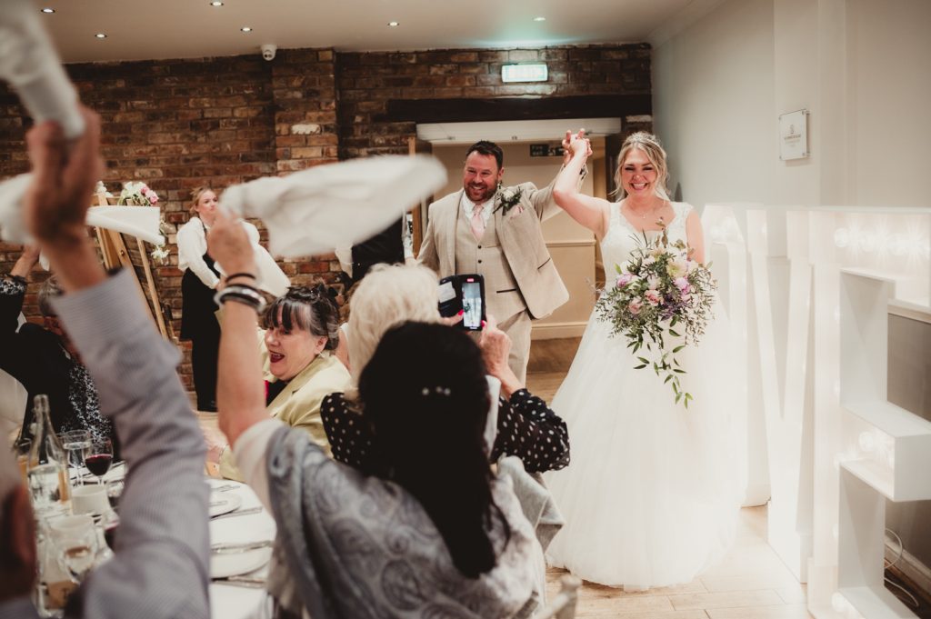 A bride and groom entering their reception at Hatherley Manor