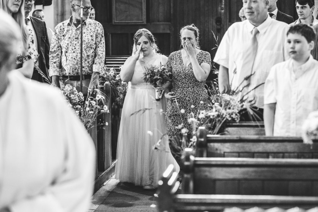 A bride and her sister feeling emotional walking down the aisle at St Marys Church in Bishopstone, Swindon.