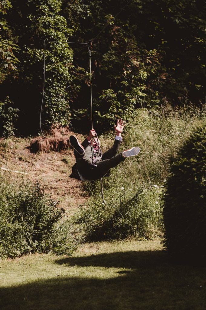 A groom swinging on a zipwire at a beautiful, fun, Cotswolds wedding