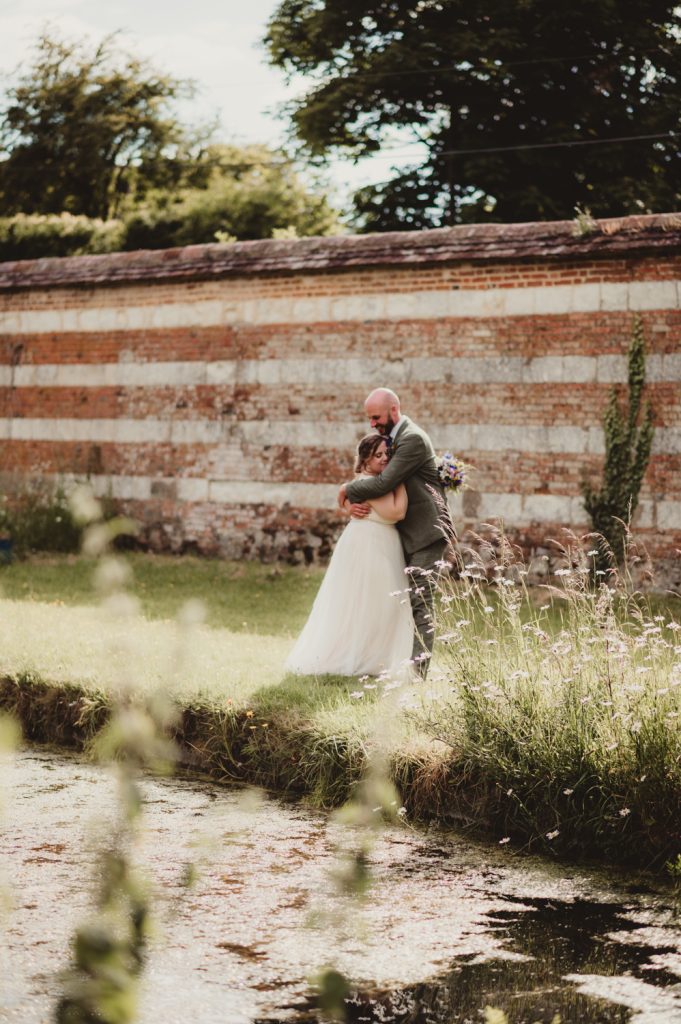 A bride and groom hugging for photos at their Cotswolds wedding.