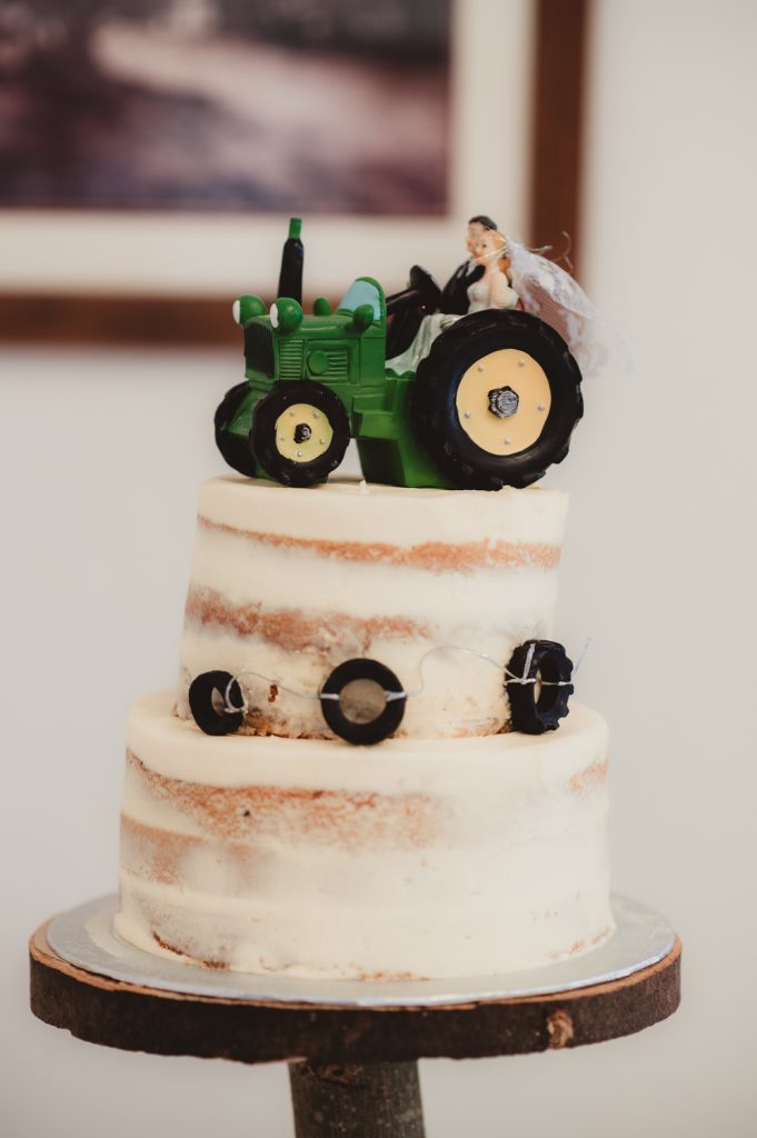 A farm inspired wedding cake with a tractor cake topper for a cotswolds farm wedding.