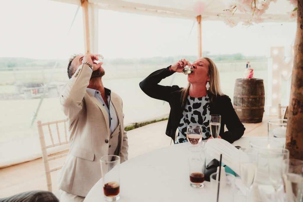 couple downing shots at hardwick Moat Weddings