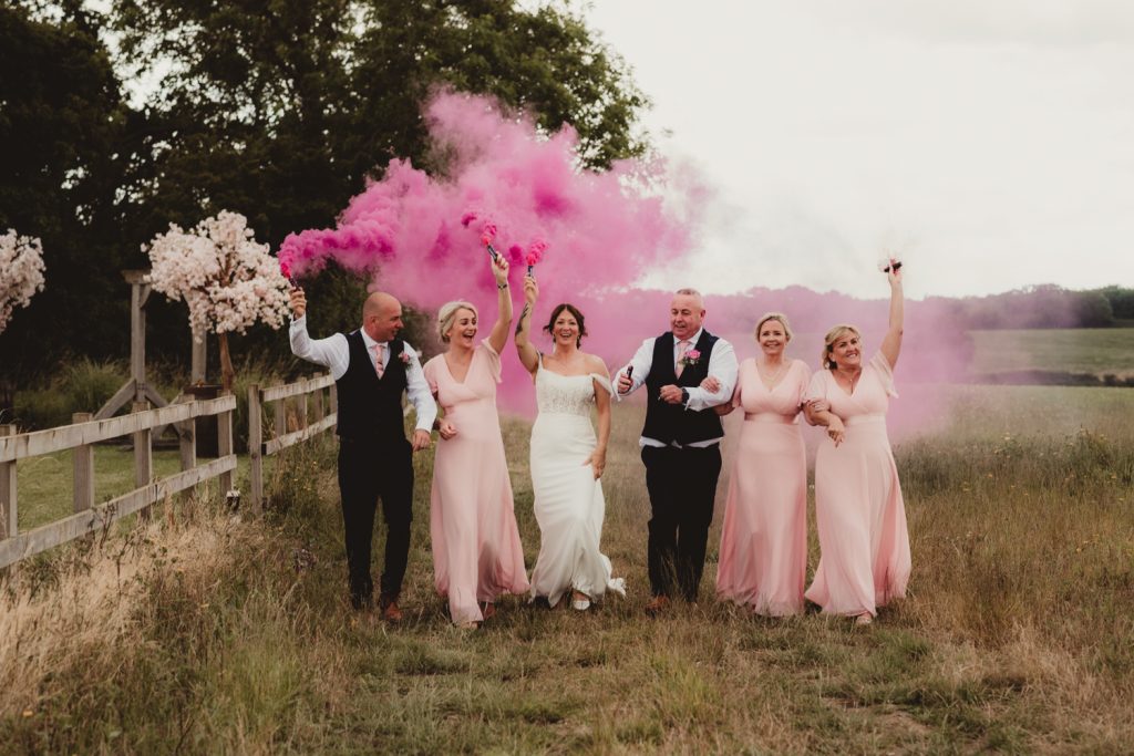 bridal party waving smoke bombs at Hardwick Moat Wedding