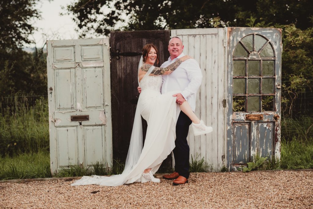 Bride and groom in front of old door backdrop at Hardwick Moat Weddings