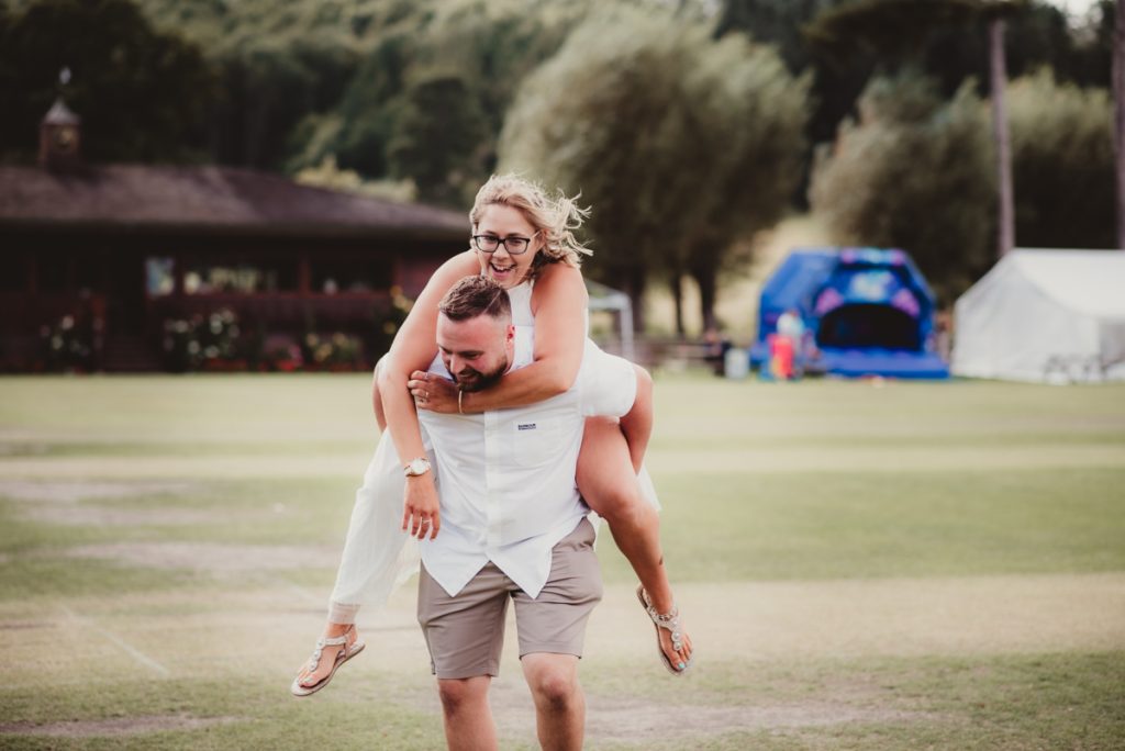 a bride having a piggyback from her husband. captured by a candid wedding photographer