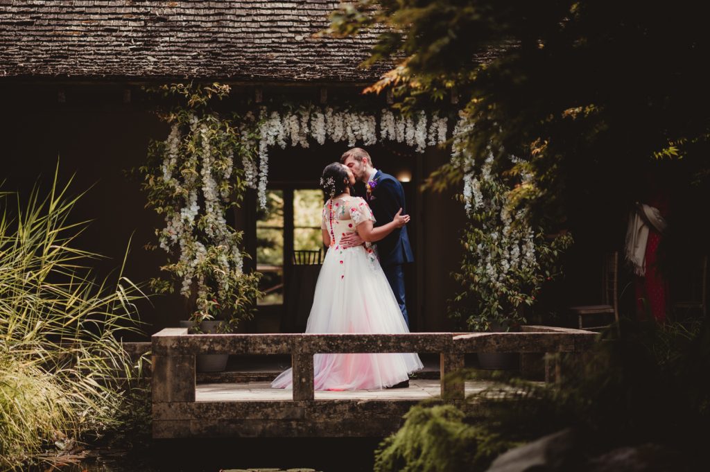 A Bride and Groom sharing thier first kiss under the cloisters at the Matara Centre. Captured by a Gloucestershire wedding photographer