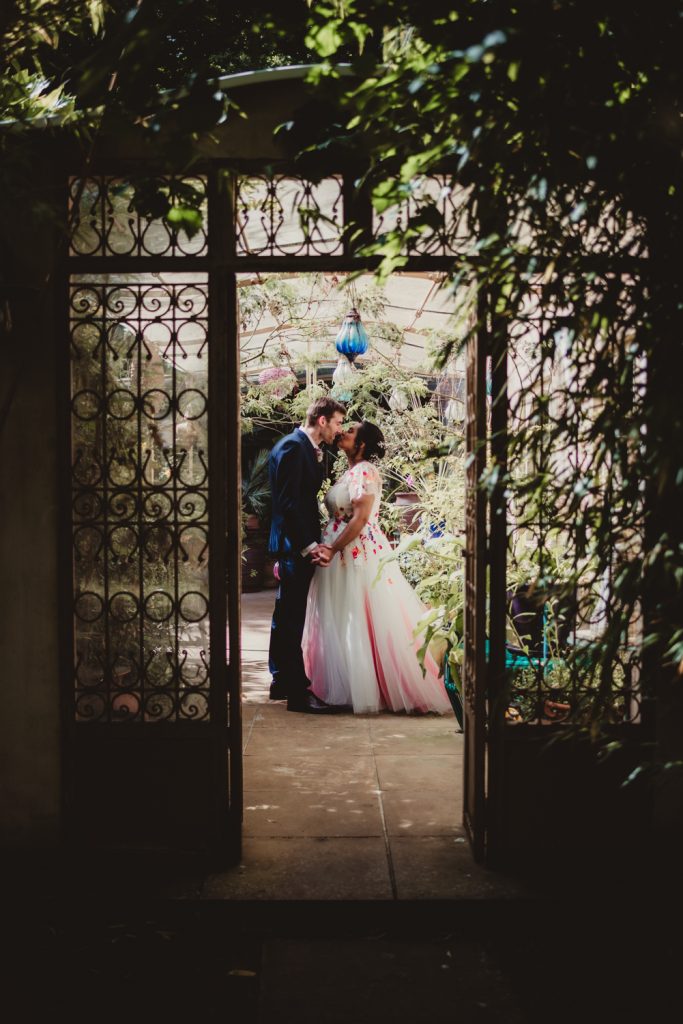 A bride and groom kissing in the outhouse of the matara centre