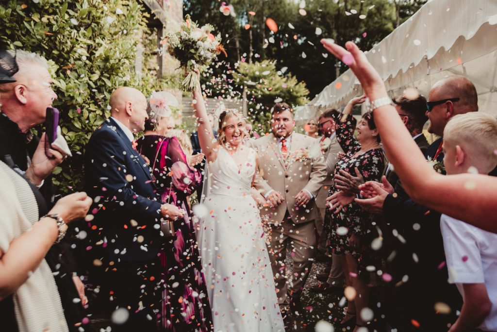 bride and groom walking through a shower of confetti at White Horse Barn in Bristol